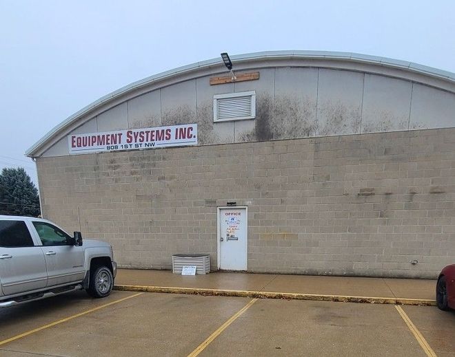 Industrial warehouse exterior with tan brick wall, white door, and Equipment Systems Inc. sign