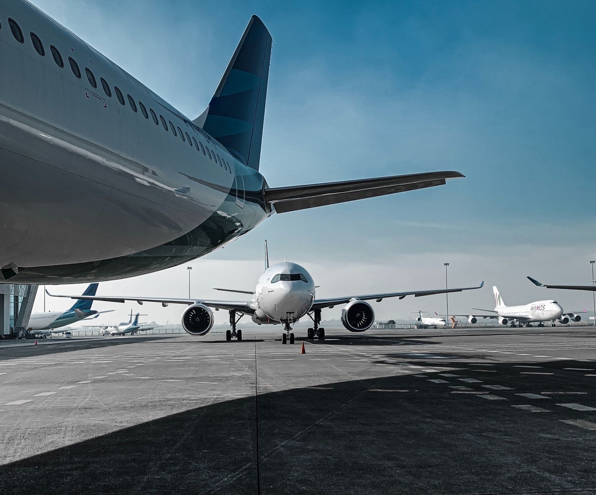 A row of airplanes are parked on a runway at an airport.