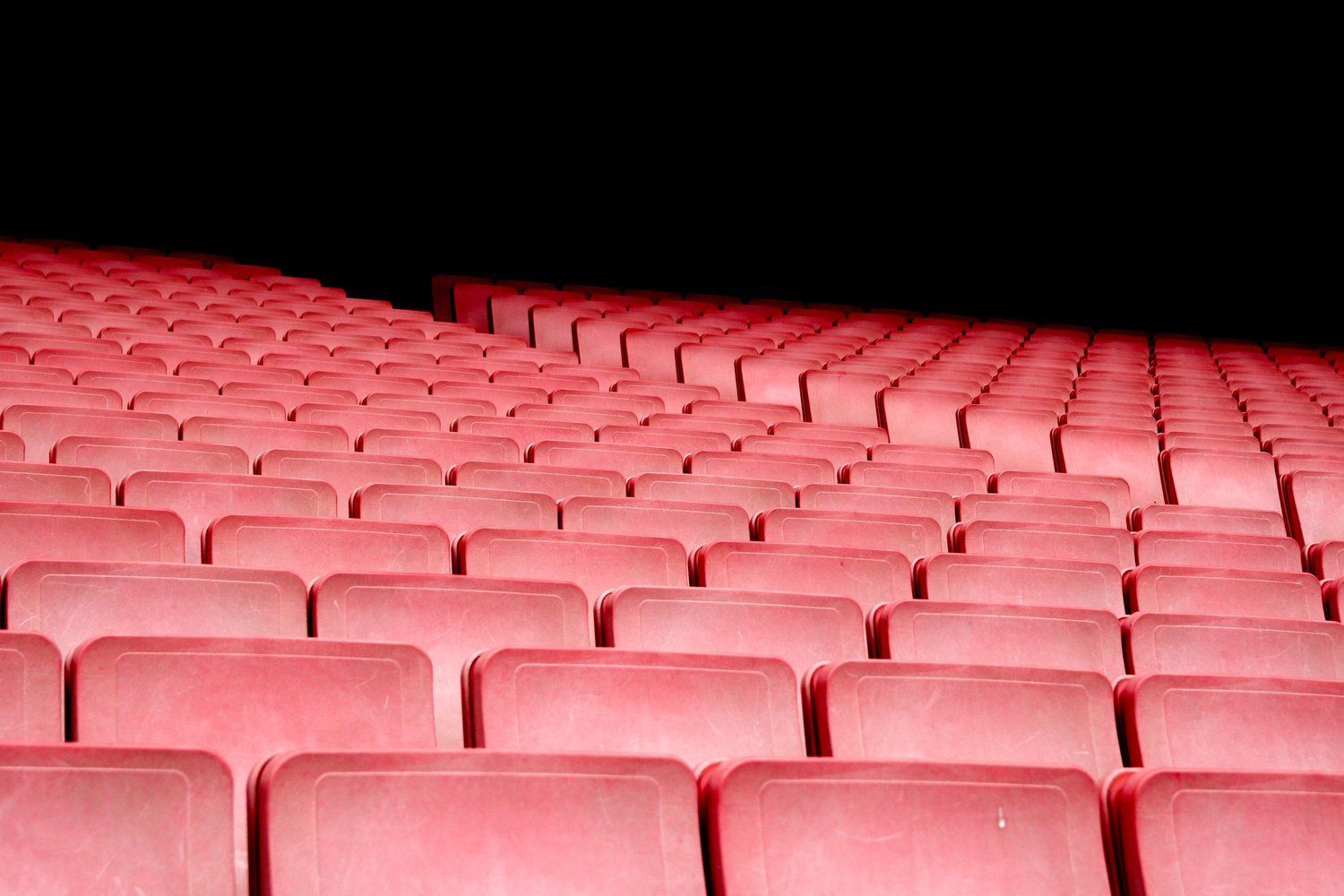 Rows of red seats in an auditorium with a black background.
