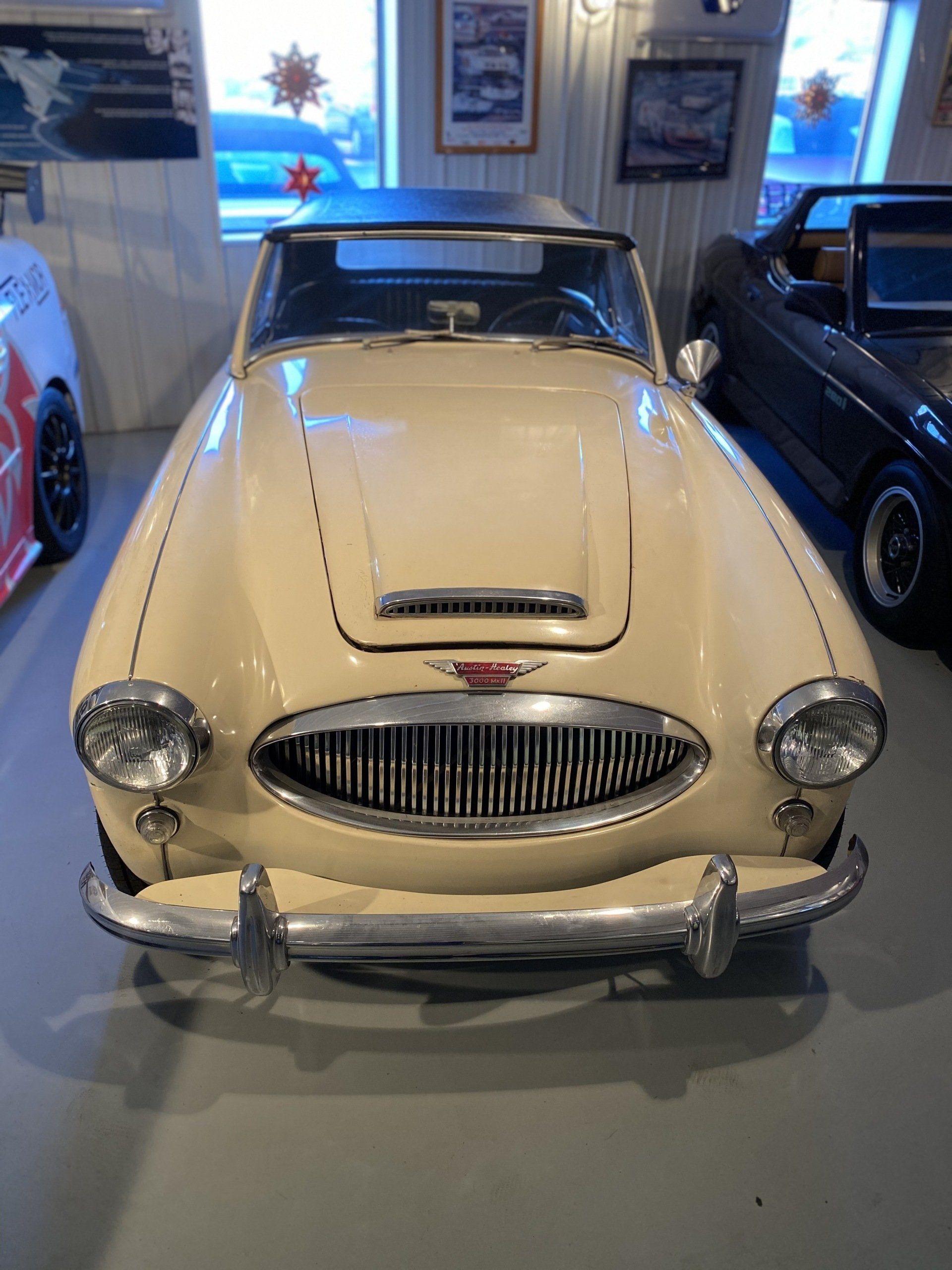 Cream-colored vintage convertible car displayed in a museum, front view.