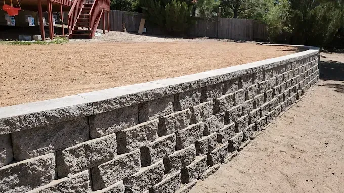 Retaining wall made of gray blocks separating a yard from lower ground.