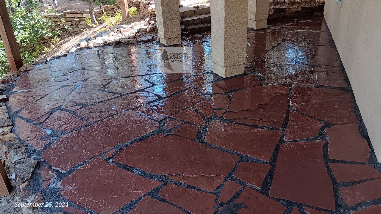 Wet red stone patio with dark grout lines under a covered outdoor area