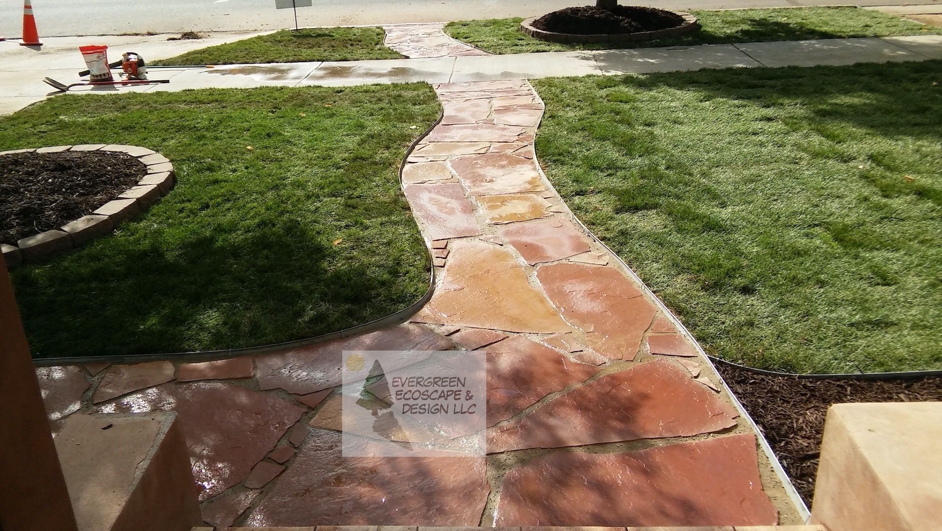 Curved stone walkway through a grassy garden with a small sign in the foreground