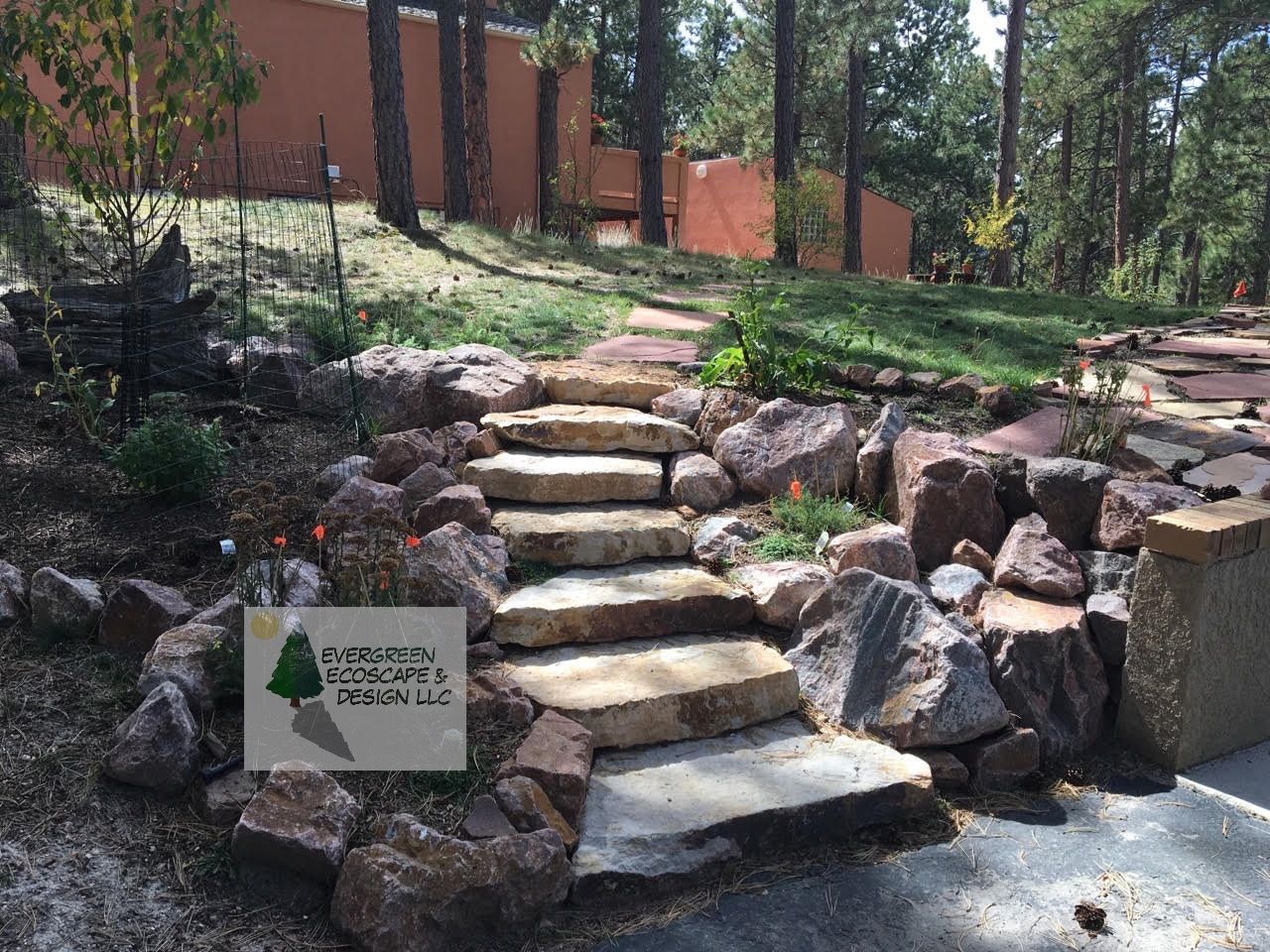 Stone steps leading up a landscaped path beside a brick building and trees