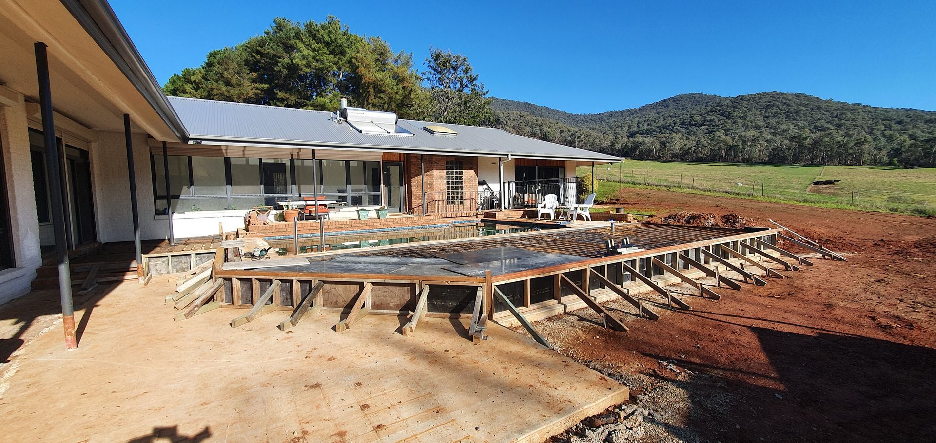 A house is being built in a field with mountains in the background.