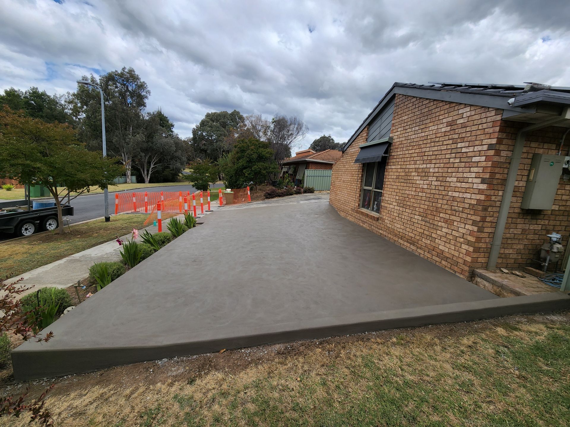 A brick house with a concrete driveway in front of it.