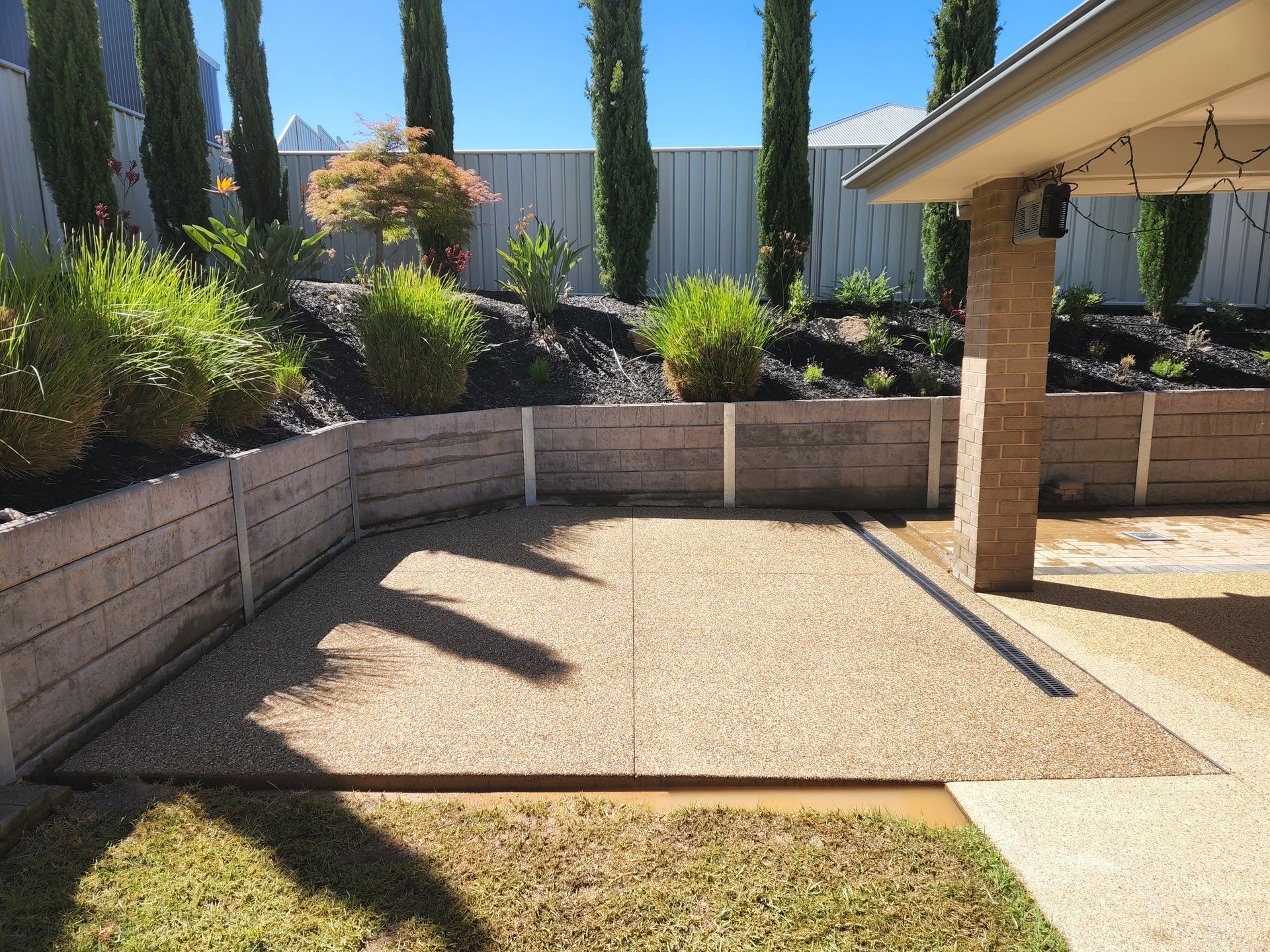A backyard with a concrete driveway and a fence