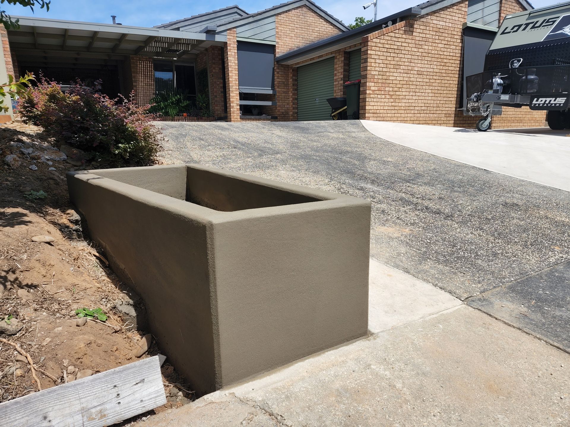 A concrete planter is sitting on the sidewalk in front of a house.