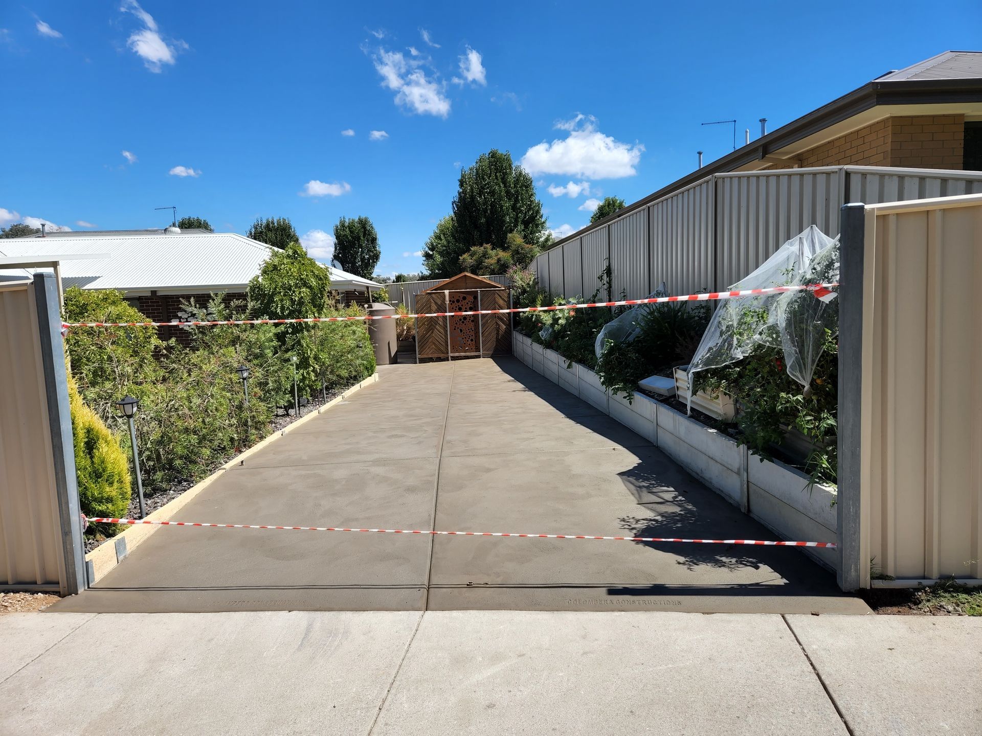 A driveway leading to a house with a white fence