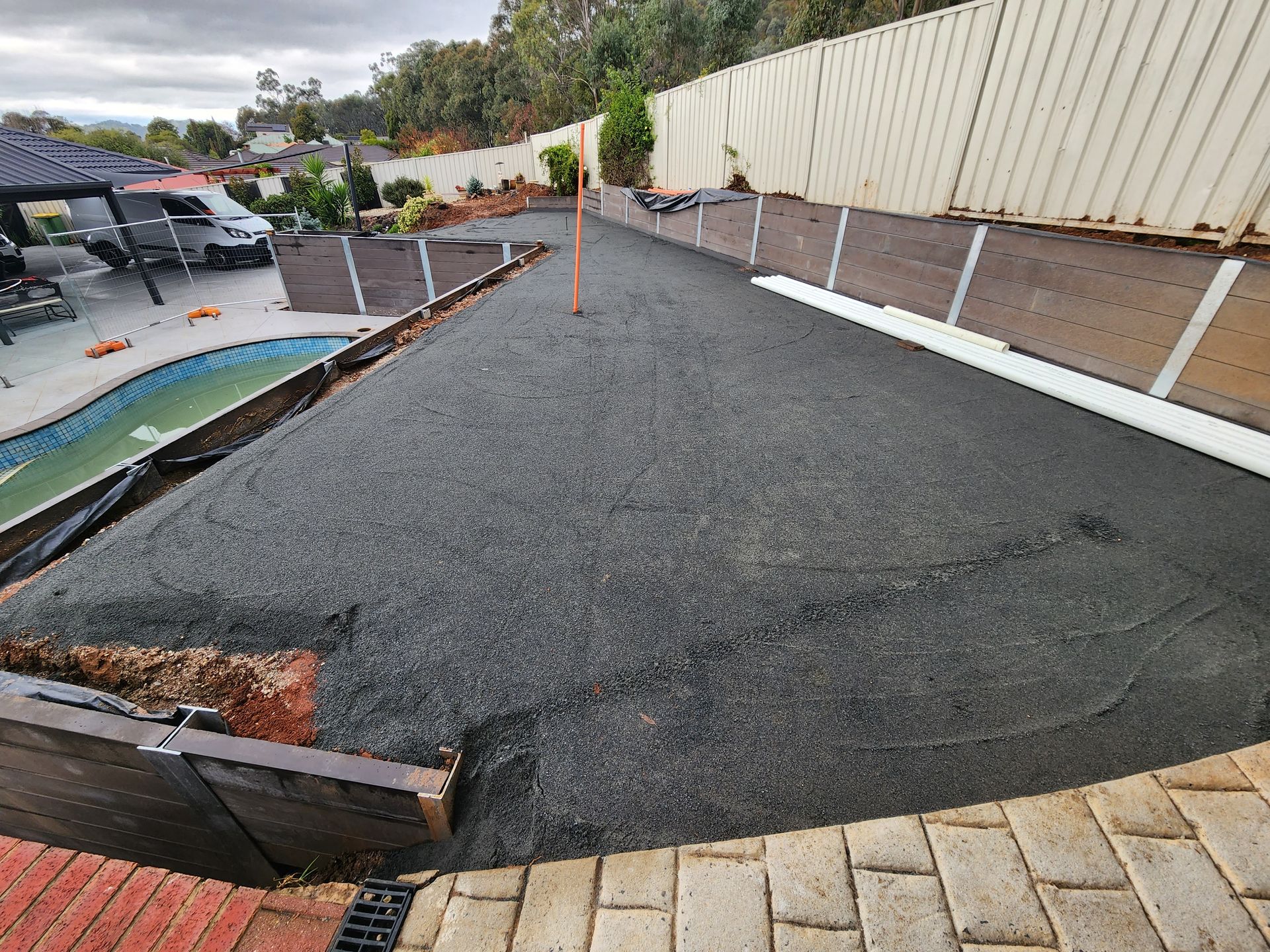 A concrete driveway is being built next to a pool.