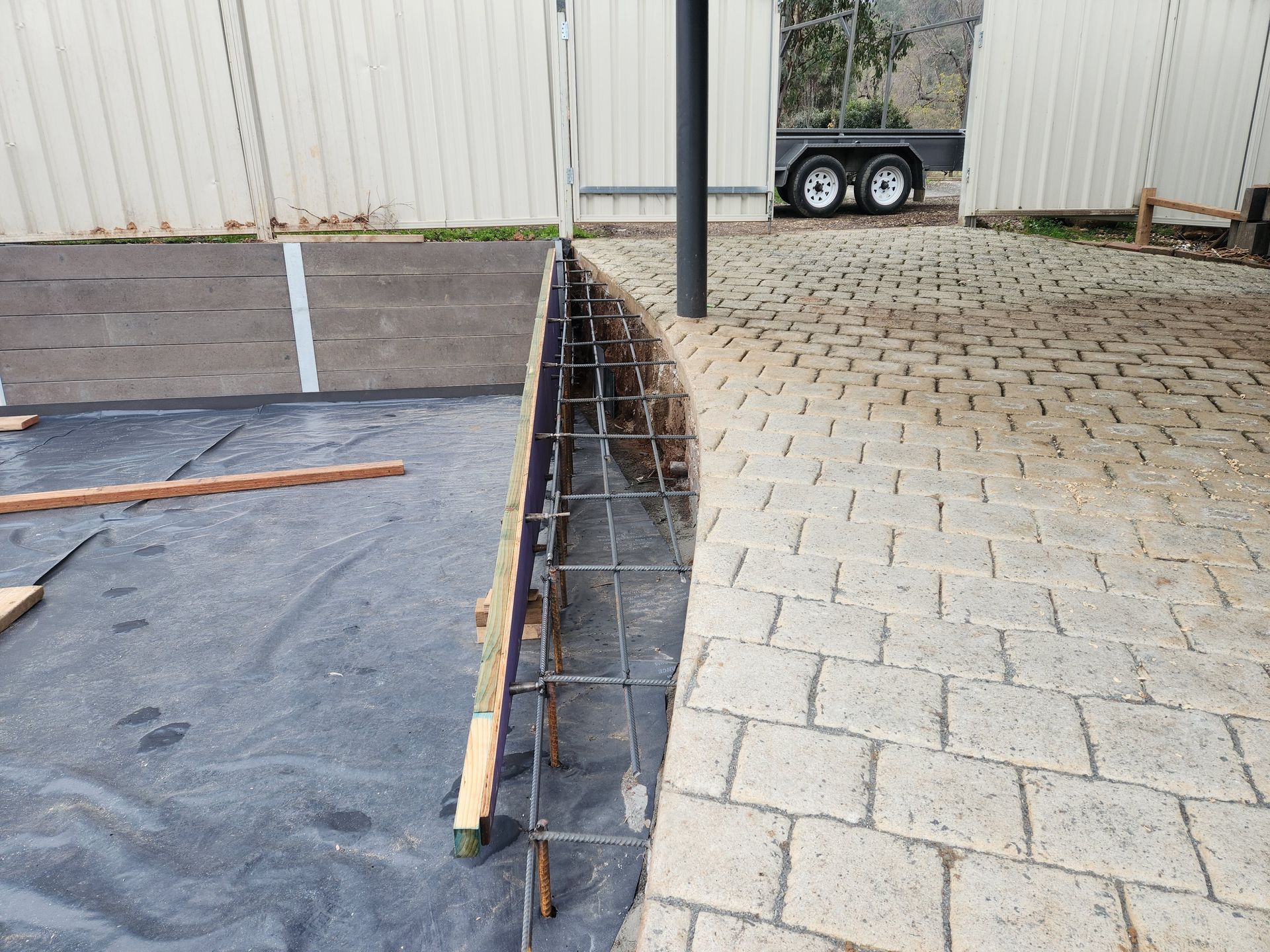 A brick driveway is being built next to a trailer.