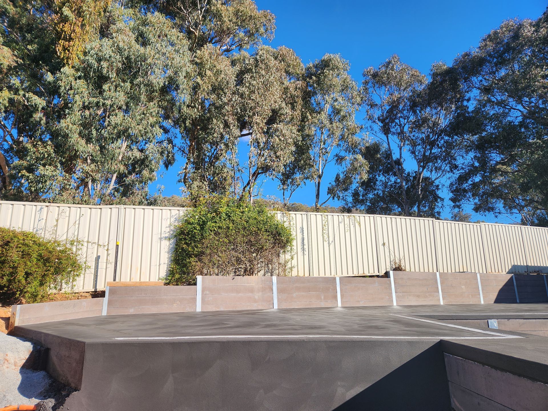 A parking lot with a fence and trees in the background