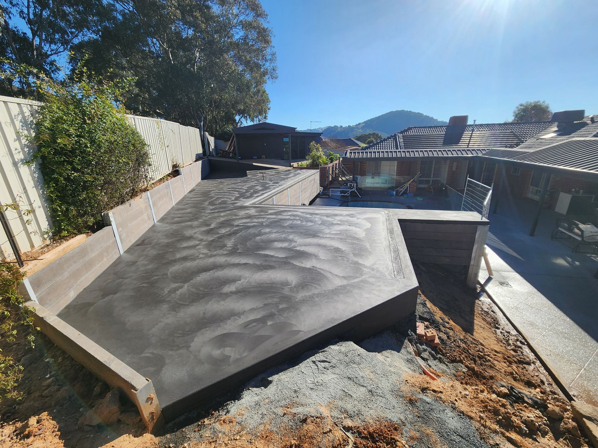 A concrete deck is being built in the backyard of a house.