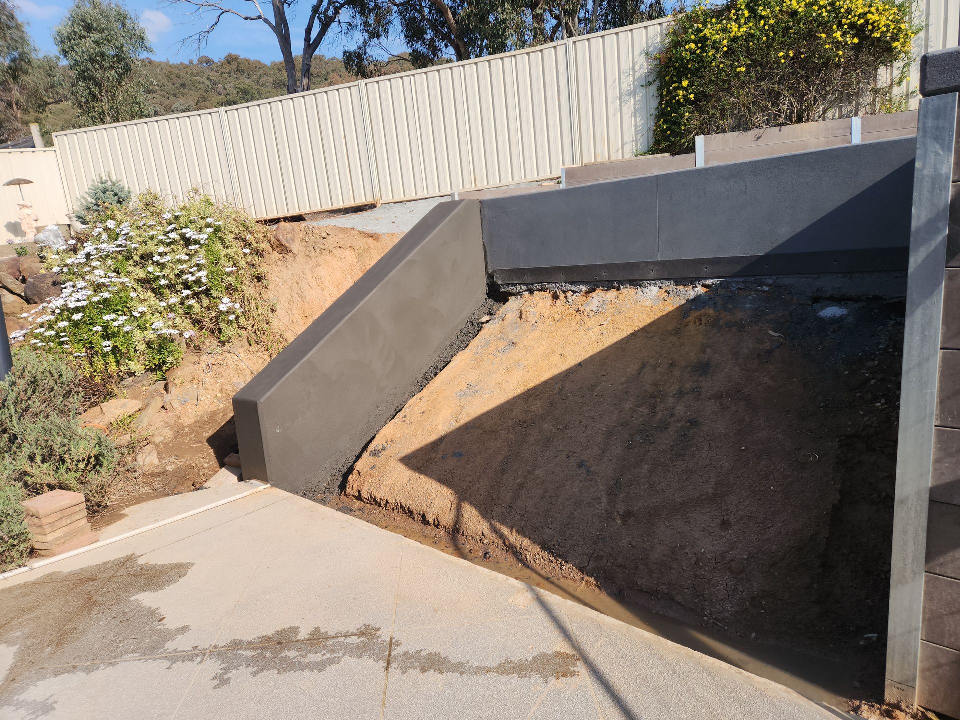 A concrete ramp is being built in the backyard of a house