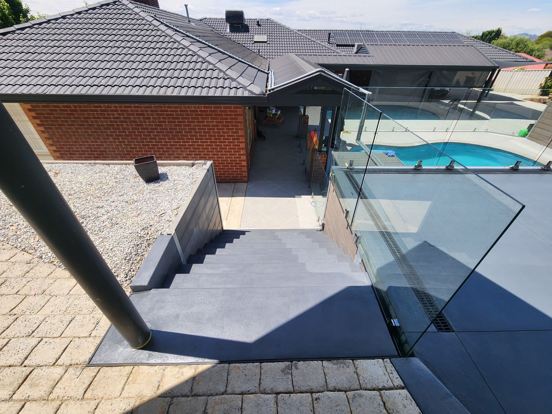 A staircase leading up to a house with a pool in the background.