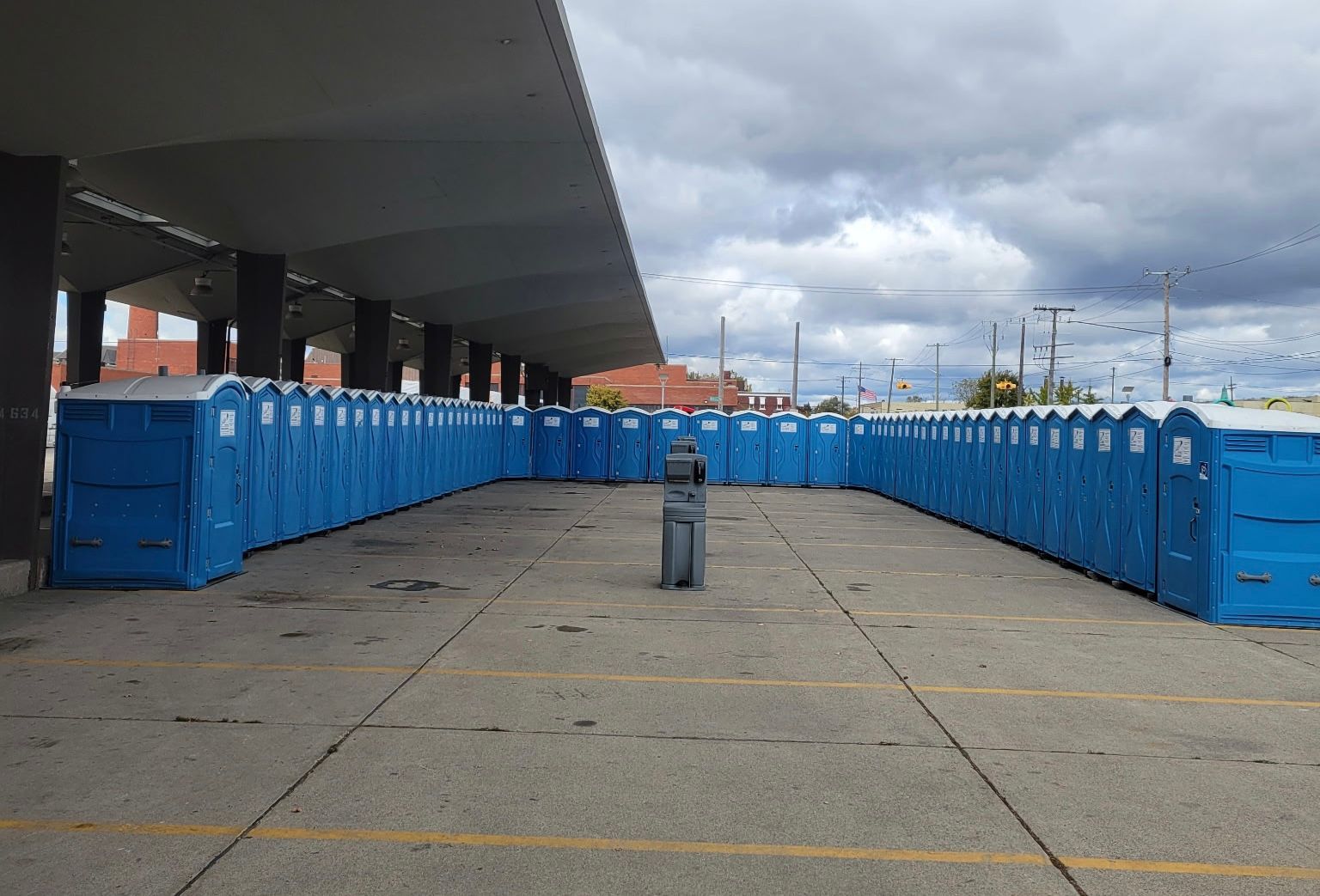 Blue barriers line an empty concrete walkway under a cloudy sky. Blue barriers line an empty concrete walkway under a cloudy sky.