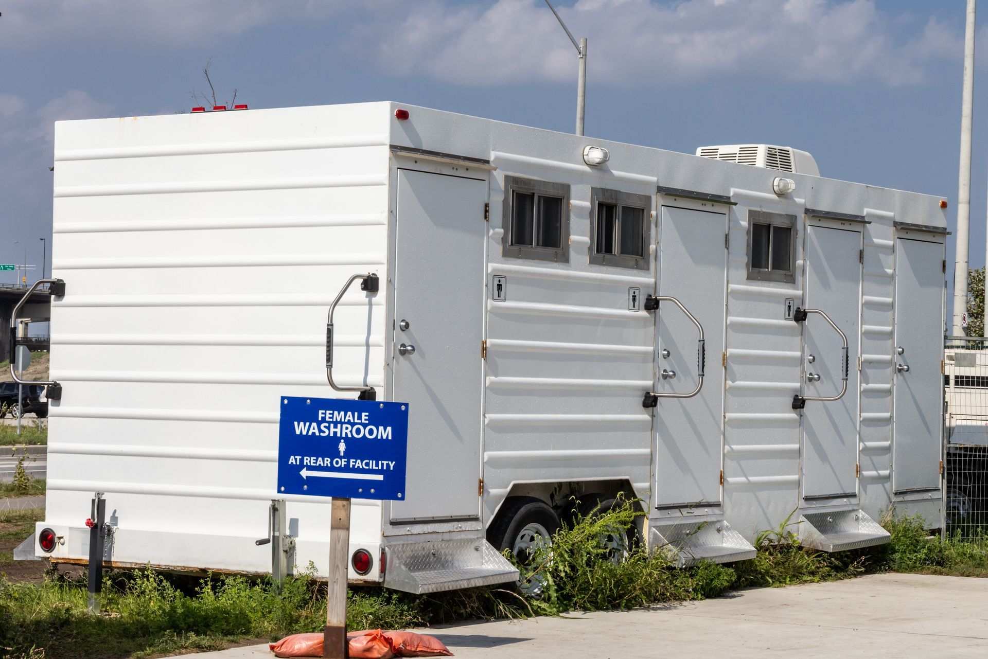 A luxury portable white restroom trailer with multiple doors parked on site A luxury portable white restroom trailer with multiple doors parked on site