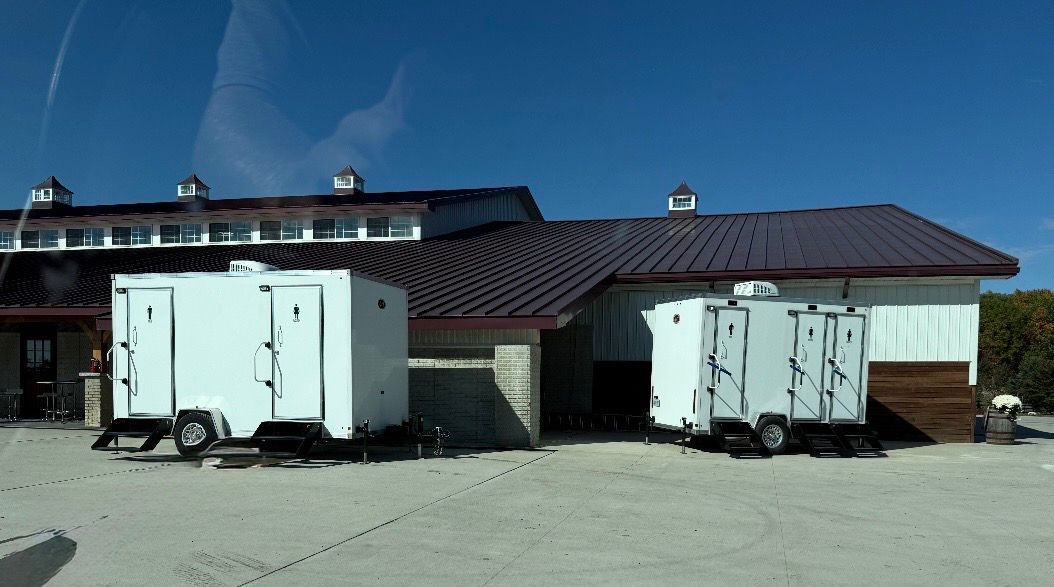 Two white refrigerated trailers parked beside a low building under a clear blue sky. Two white refrigerated trailers parked beside a low building under a clear blue sky.
