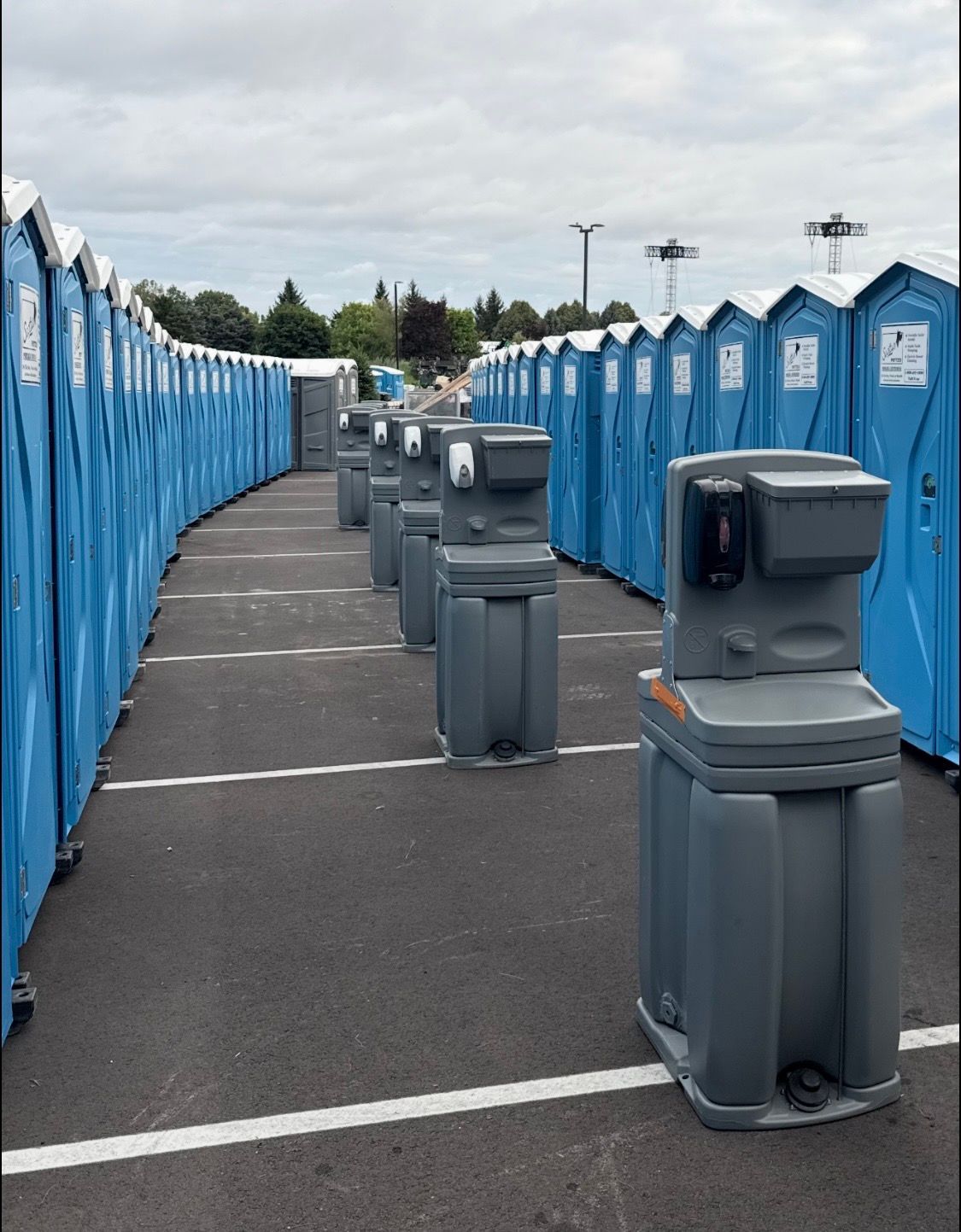 Portable toilet units for rent lined up at an outdoor event site