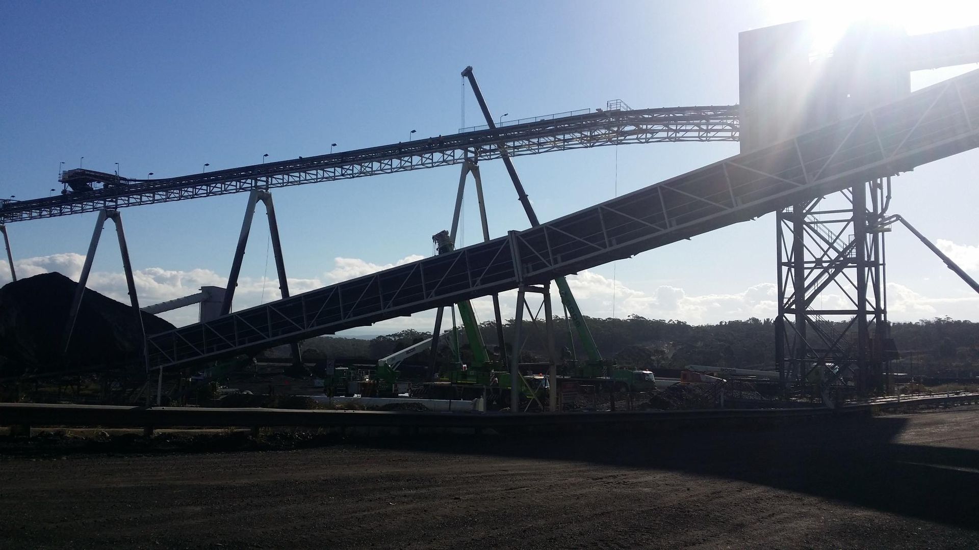 a conveyor belt is silhouetted against a blue sky in a factory