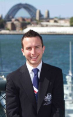 a man in a suit and tie stands in front of a body of water