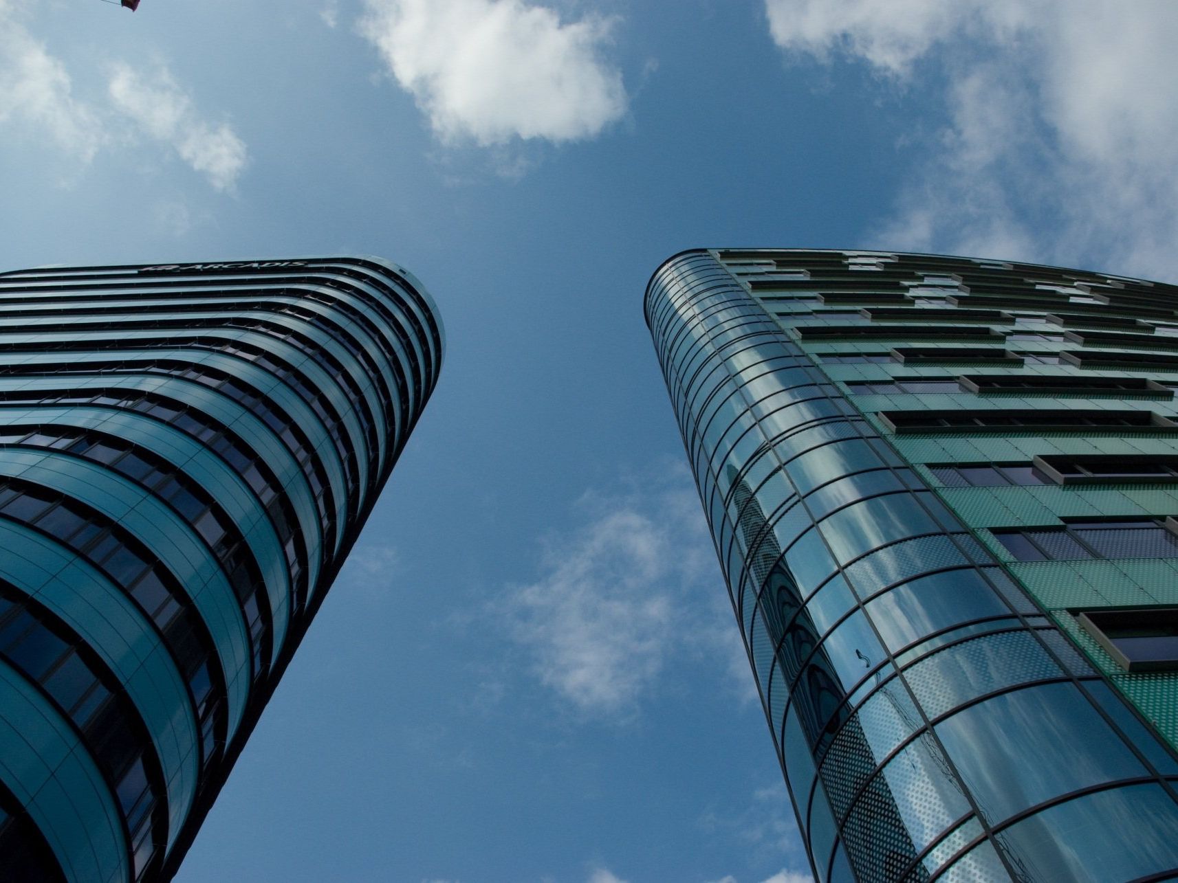 Looking up at two tall buildings with a blue sky in the background