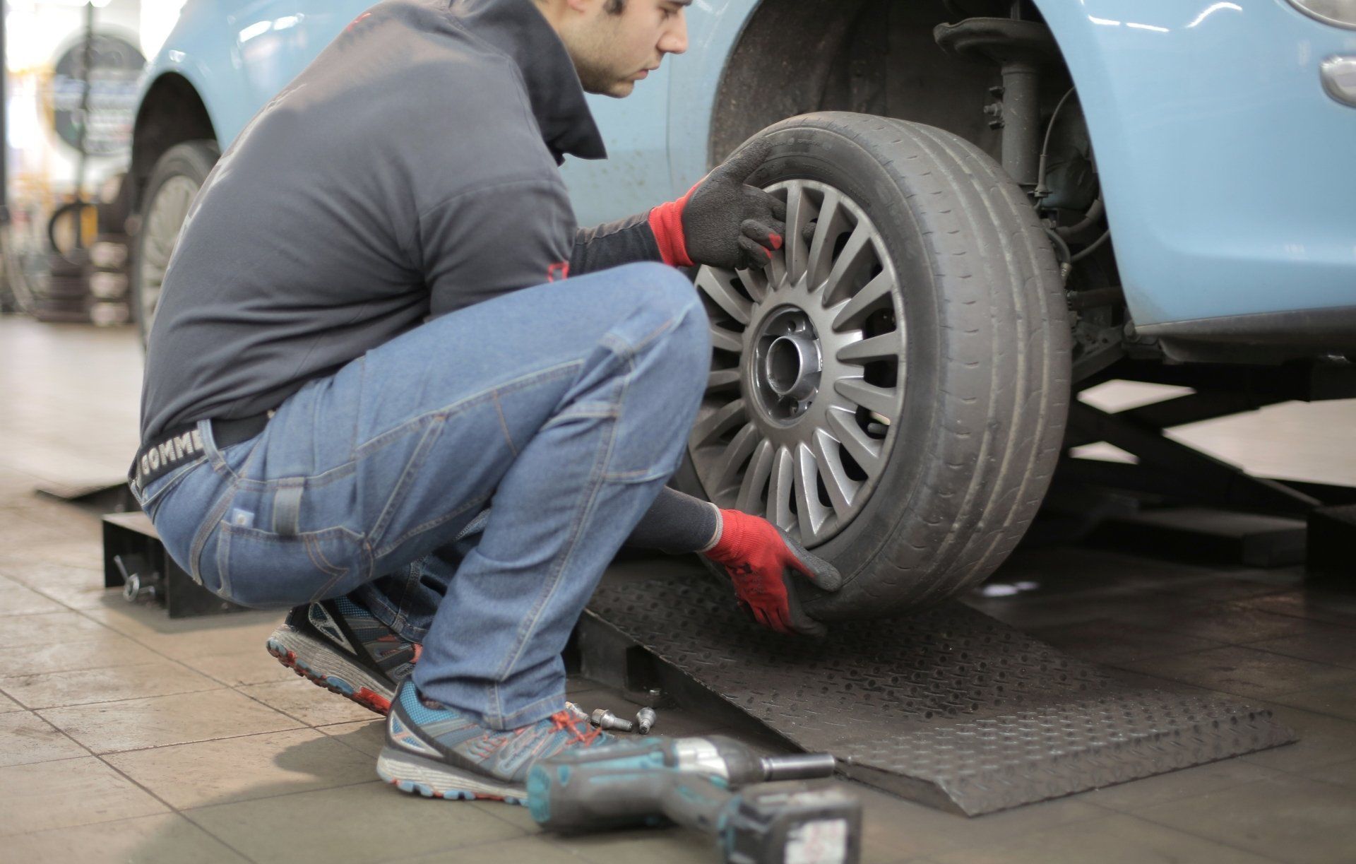 Changing a tire A man is changing a tire on a car in a garage.