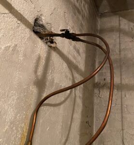 Small copper tubes like these coming through a foundation wall could be a clue that there is a buried oil tank in the yard.