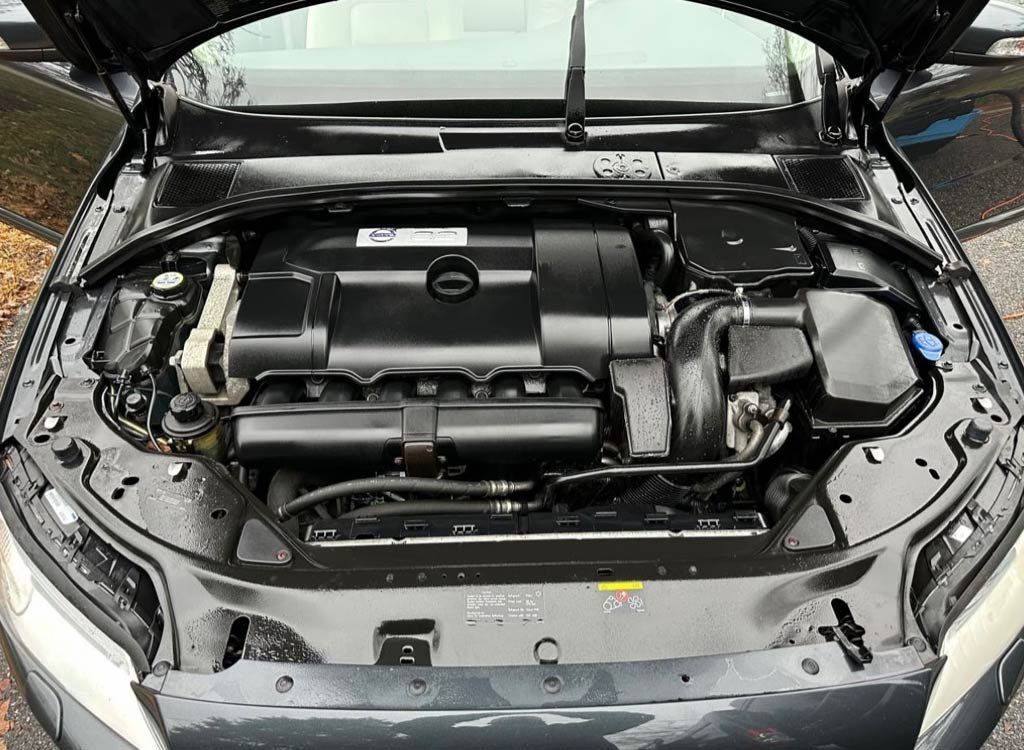 Car engine compartment, black with various mechanical components visible.