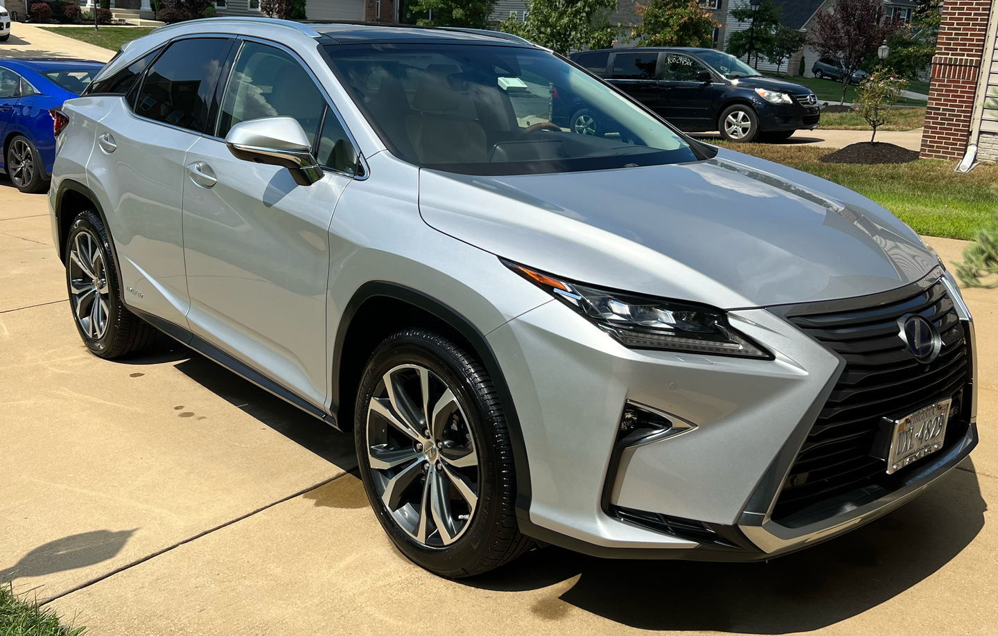 Silver Lexus RX SUV parked on a paved driveway in front of a house.