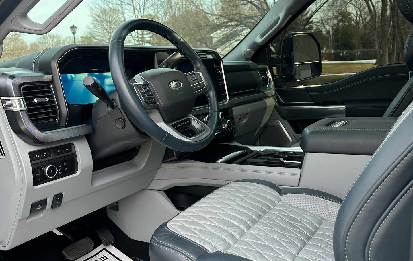 Interior of a Ford F-150 truck with a gray and black quilted leather seat and steering wheel.