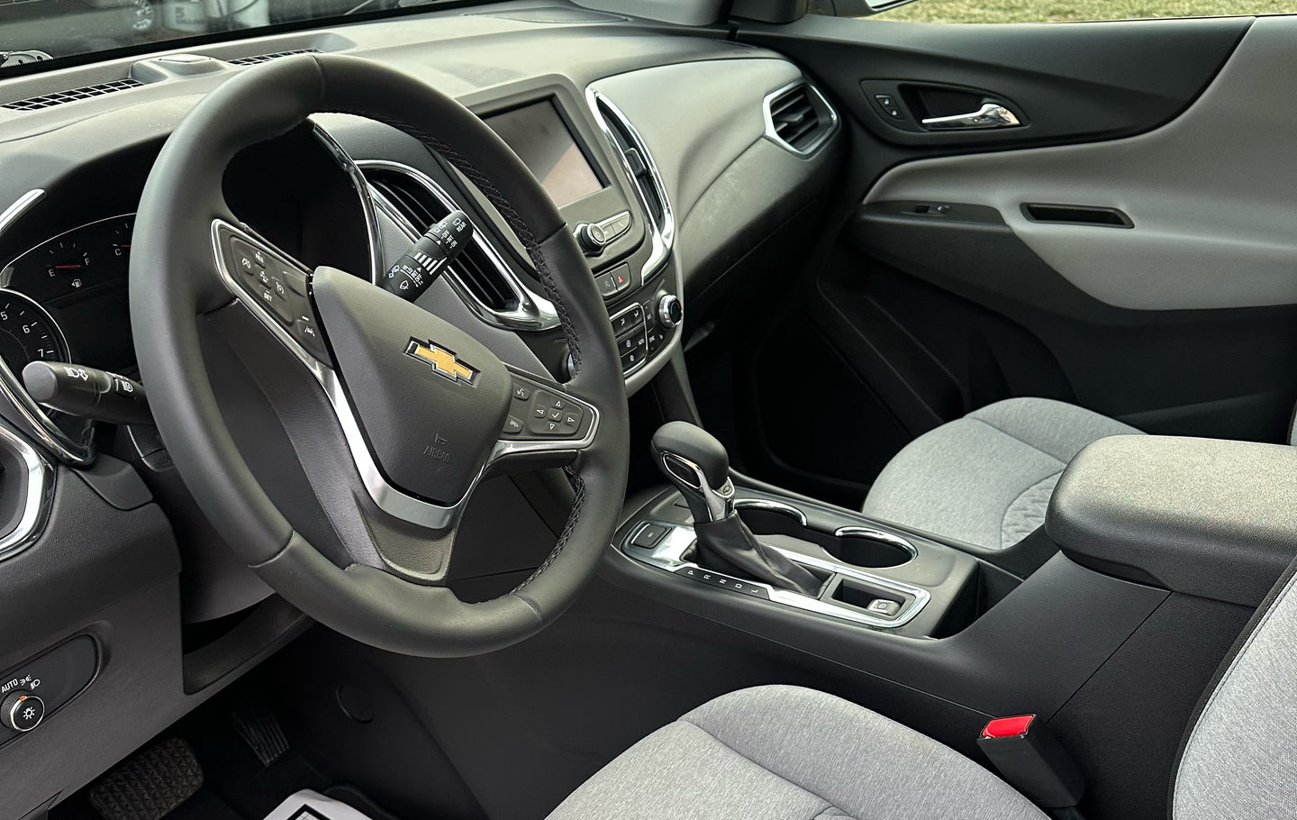 Interior of a Chevrolet SUV with a black steering wheel, gray dashboard, and light gray seats.
