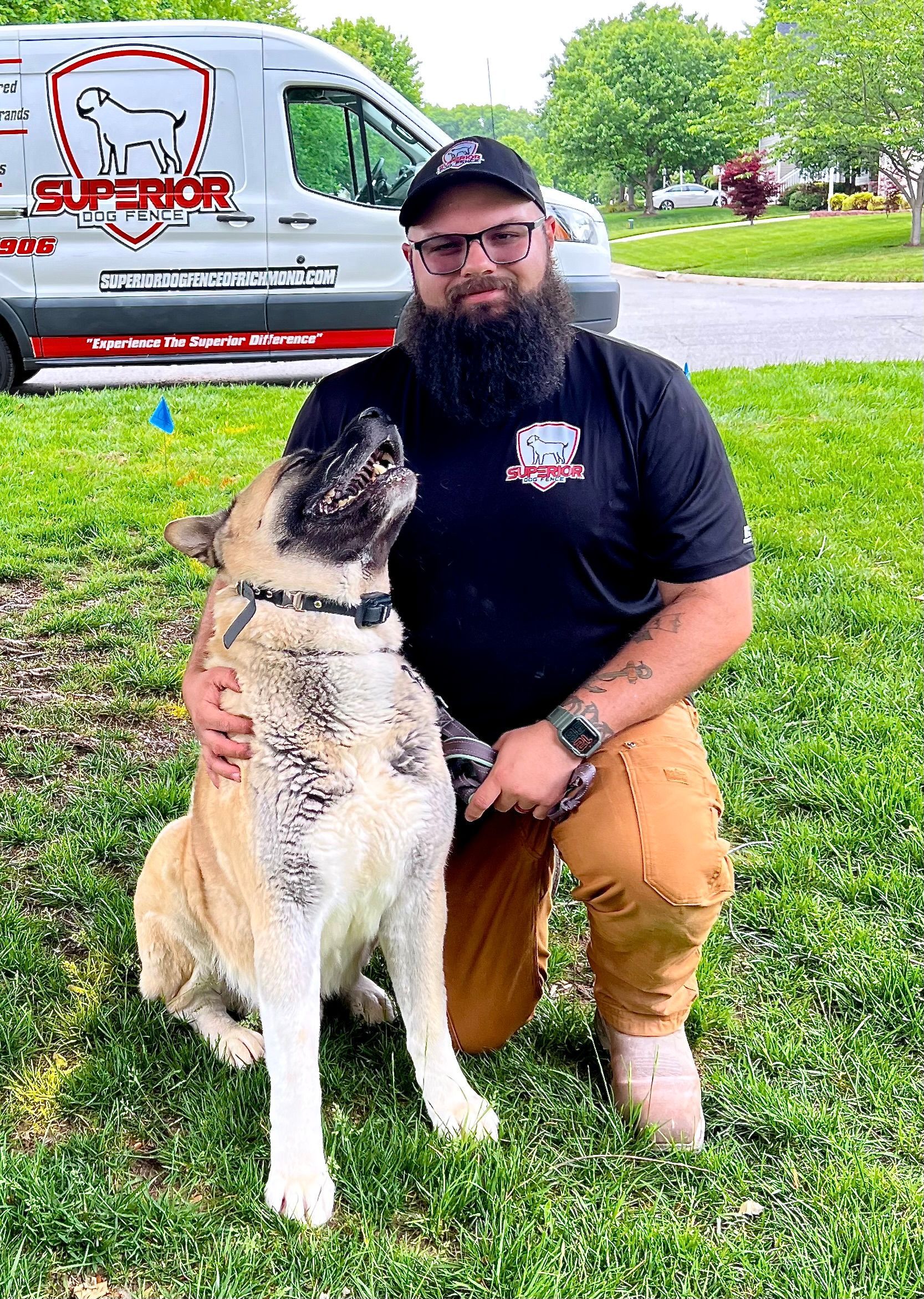 We can put big and small dogs on our underground dog fence system! A man with a beard is kneeling down next to a dog in the grass.
