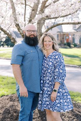 couple  poses under a tree. Father with beard, mother in blue dress.