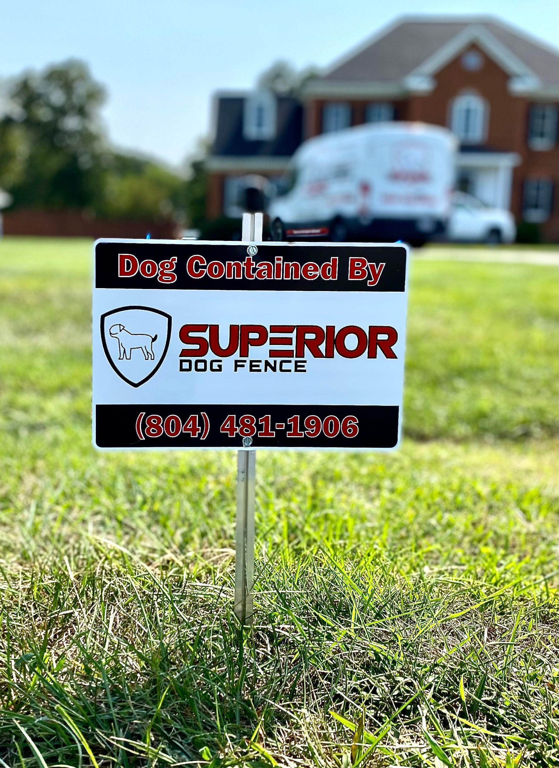Keep your dog in your yard with Superior Dog Fence! A superior dog fence sign is sitting in the grass in front of a house.