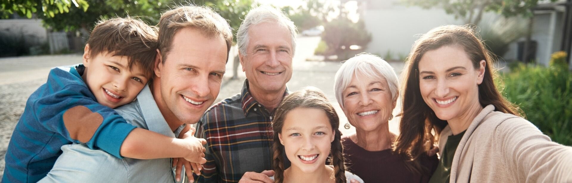 A group of six people posing for a close-up outdoor group photo, all smiling warmly at the camera.
