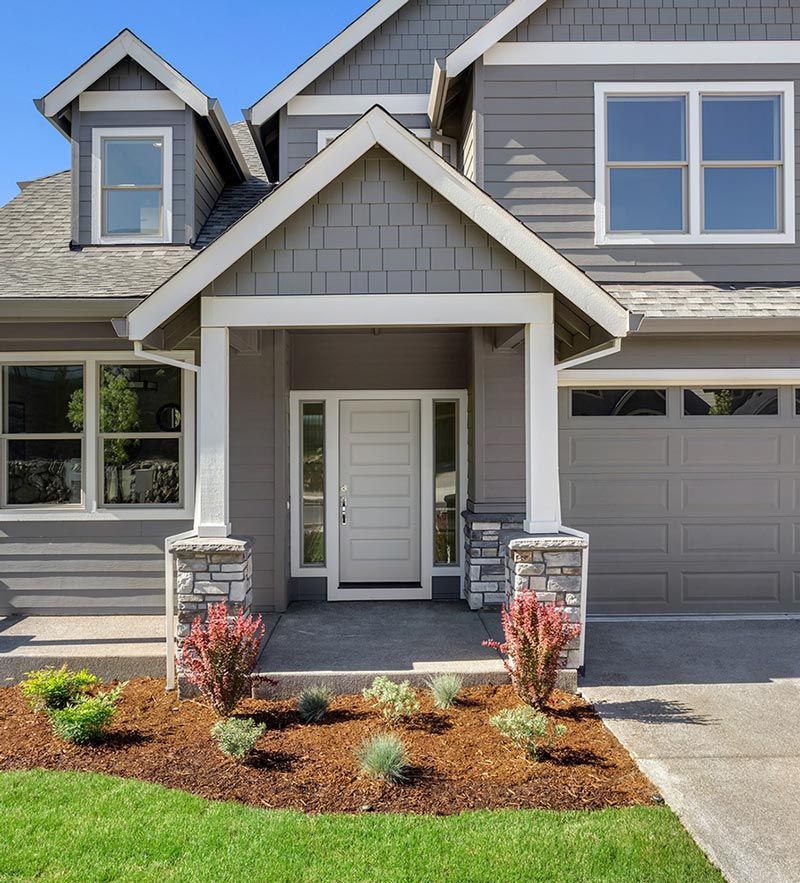 A gray house with white trim and a white door