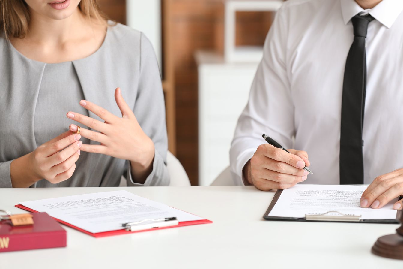 Two people in business attire discussing paperwork across a desk