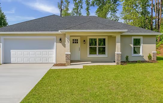 Single-story beige house with white garage and green lawn under a blue sky