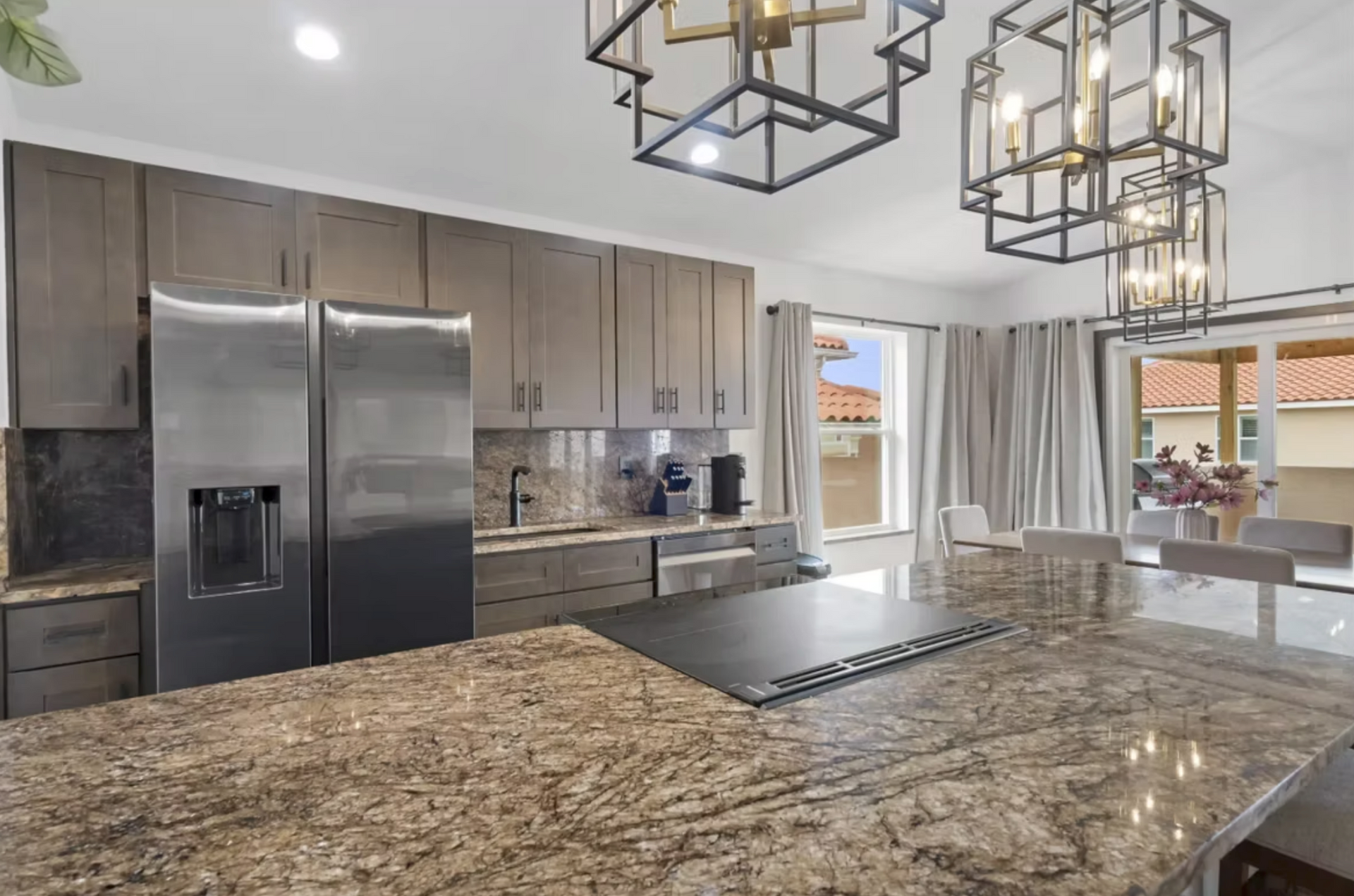 Modern kitchen with granite island, stainless steel appliances, and large pendant lights