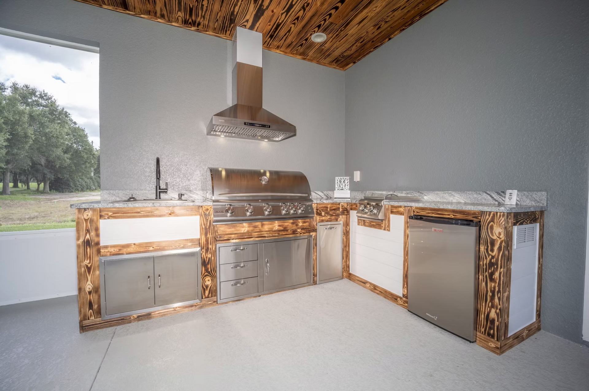 Modern kitchen with granite counters, stainless steel appliances, and a large range hood