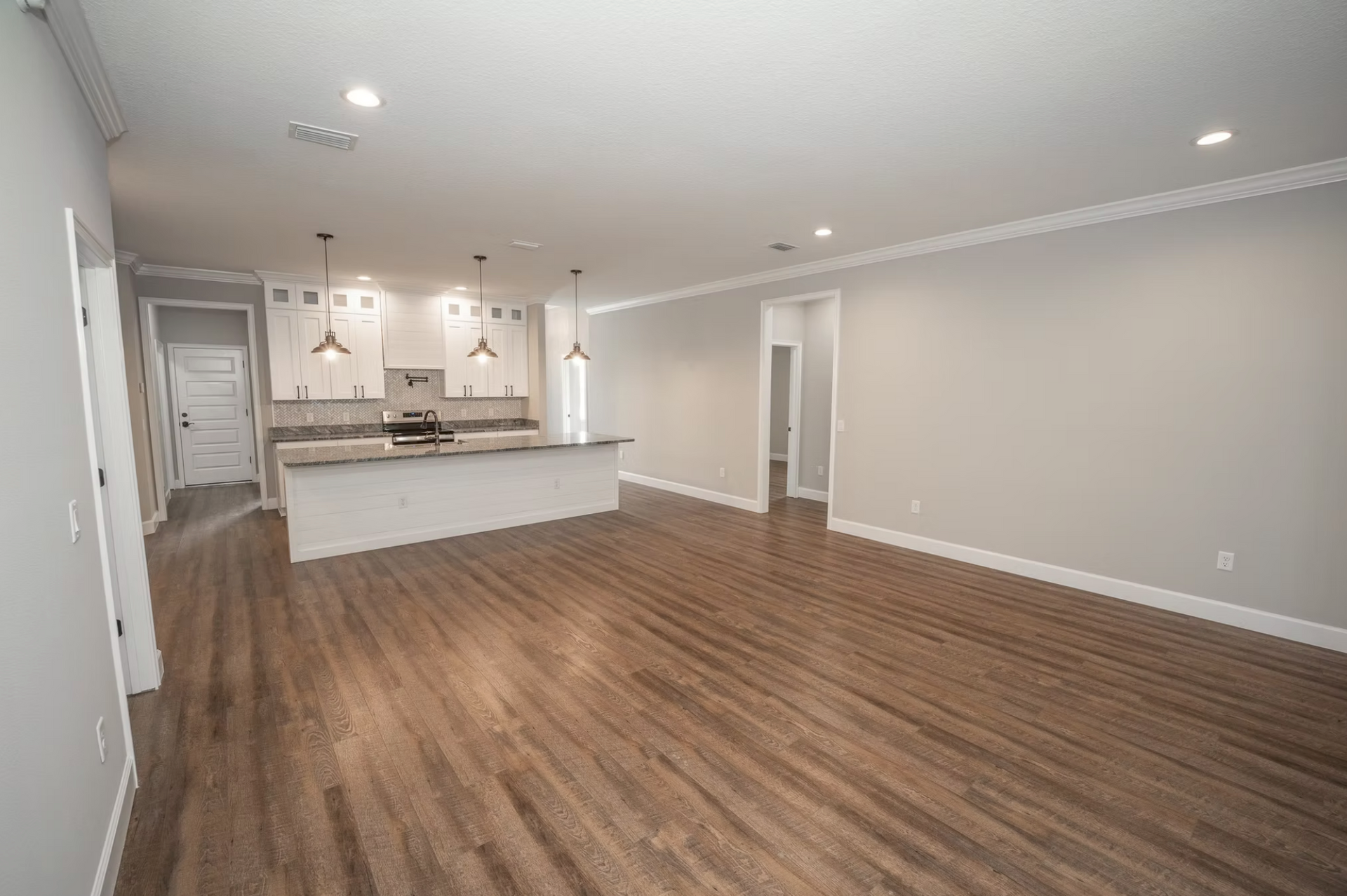Spacious empty living room with wood floors and a modern open kitchen