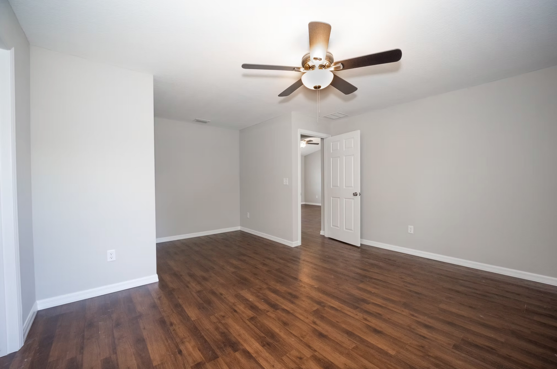 Empty room with wood floors, white walls, and a ceiling fan.