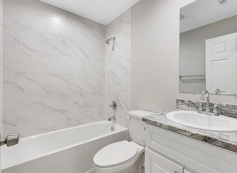 Bright white bathroom with tub, marble tile shower, and granite vanity with sink and mirror