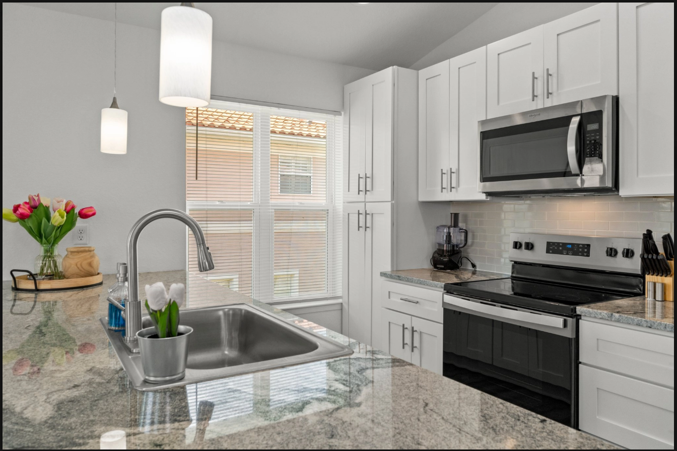Modern kitchen with white cabinets, stainless steel appliances, granite counters, and a center island sink