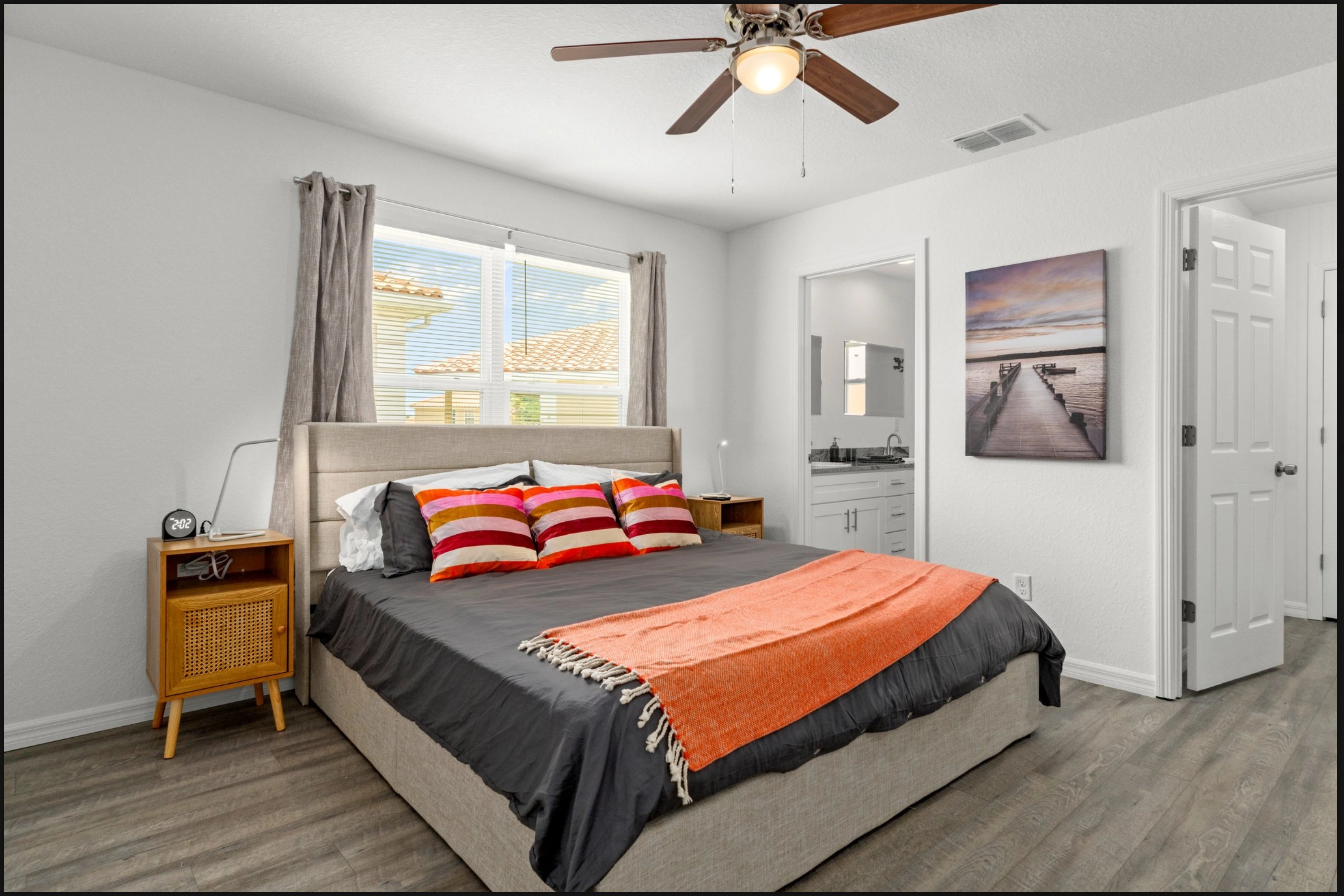 Bright bedroom with a bed, gray walls, orange throw, window, ceiling fan, and closet door