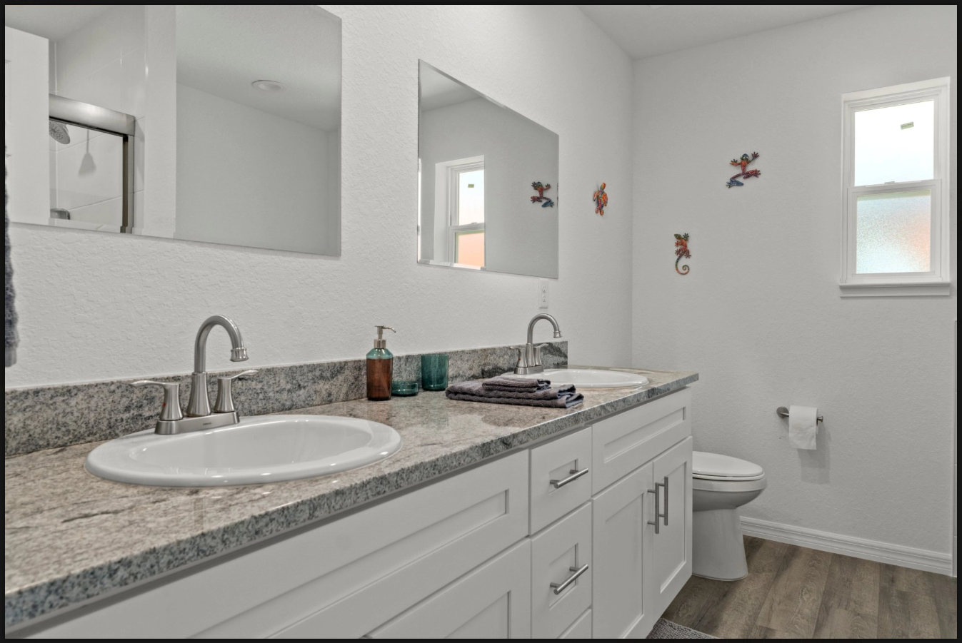 Bright bathroom with granite vanity, round sink, mirror, toilet, and small wall windows