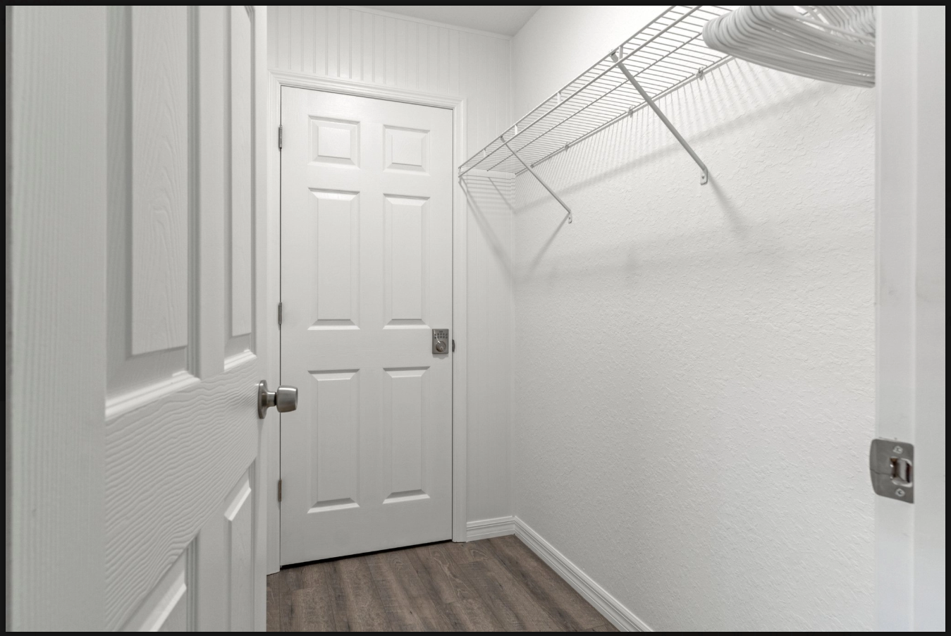 Small white closet with wire shelving, a closed door, and wood-look flooring.