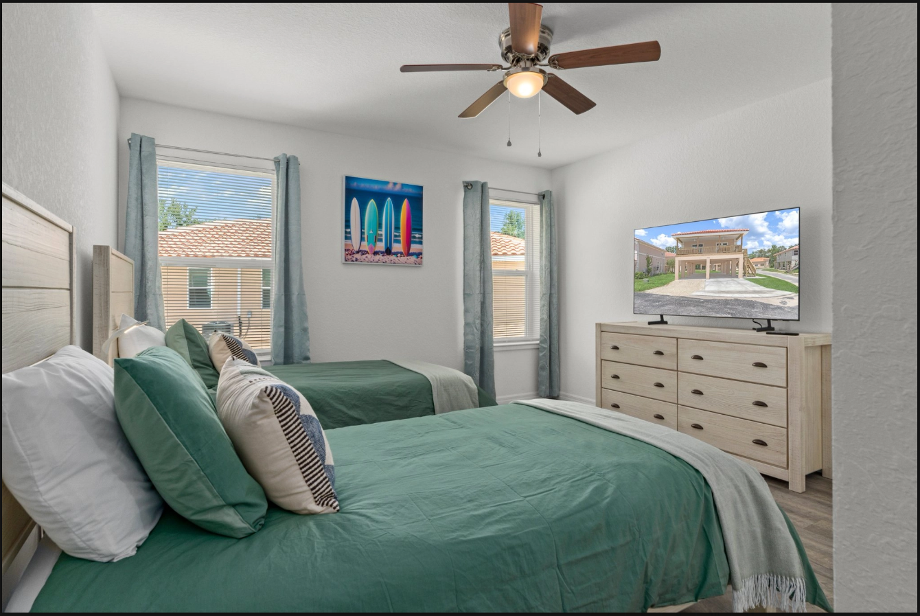 Bright bedroom with green bedding, ceiling fan, dresser, and large windows overlooking houses