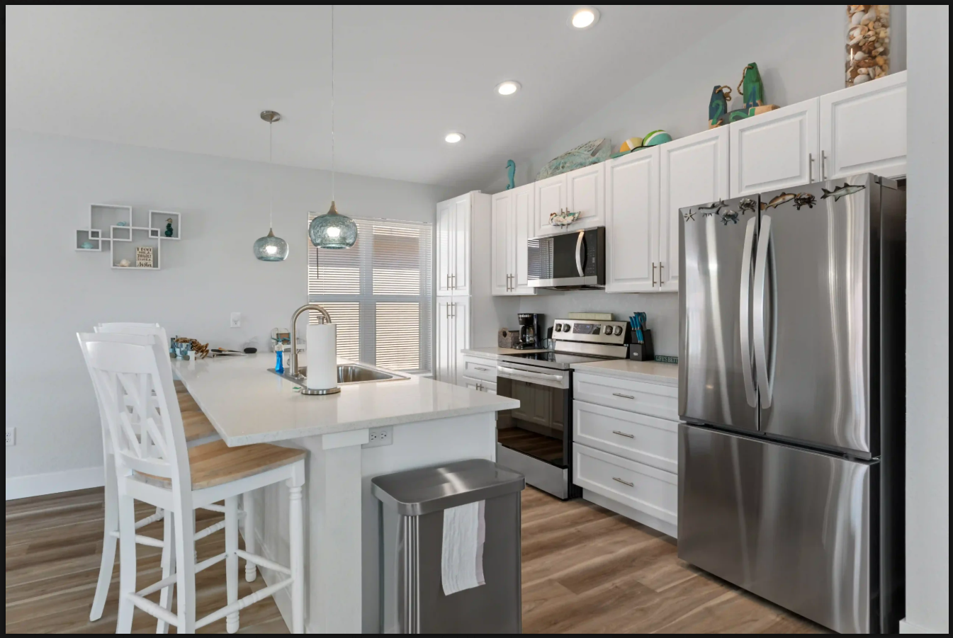 Bright modern kitchen with white cabinets, stainless steel appliances, and a large island with bar stools
